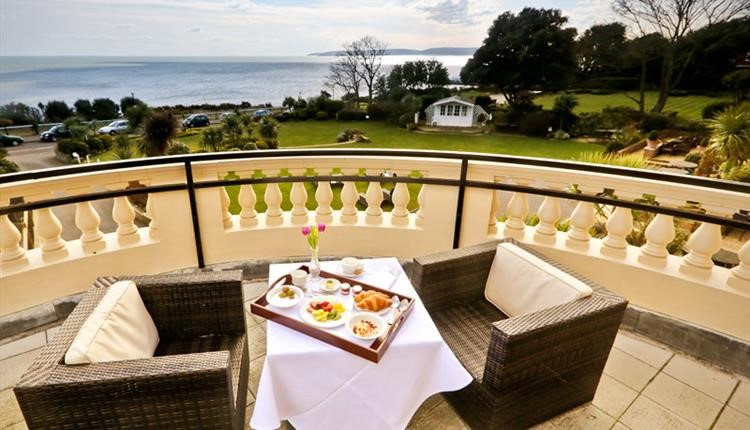 Continental breakfast laid up on table with views overlooking the garden and sea 
